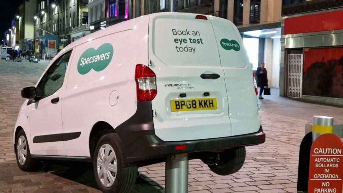 The rear of a white Specsavers branded van suspended in the air on an automatic bollard